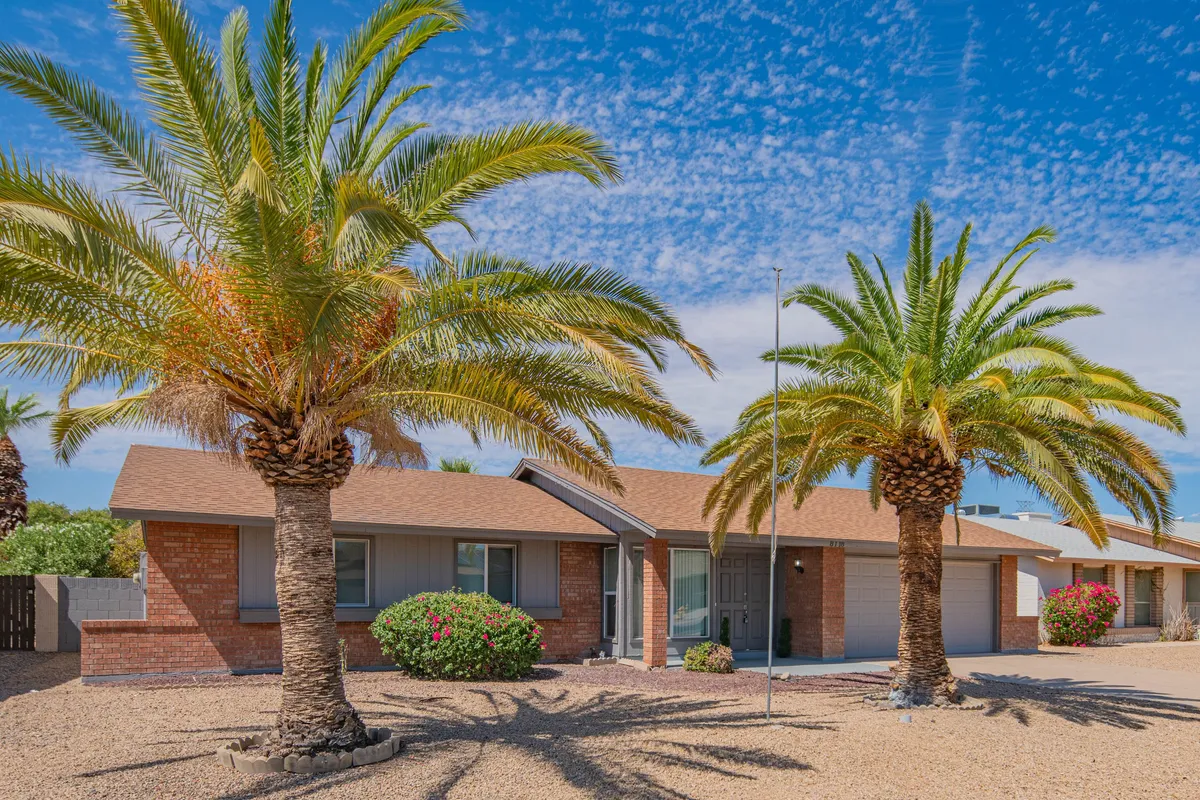 This image shows the inviting exterior entrance of Villa Theresa, framed by tall palm trees and vibrant flowering bushes. The front door is visible, surrounded by lush landscaping, setting a welcoming scene for guests arriving at the property.