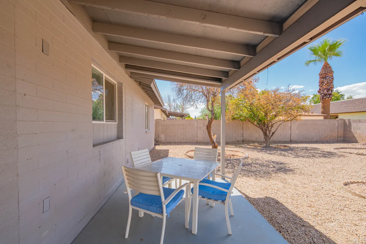 A relaxed outdoor dining area with a table, palm tree, and a view of the surrounding landscape. The space appears designed for informal social gatherings, casual meals outside, and gives a sense of the Arizona outdoor lifestyle.
