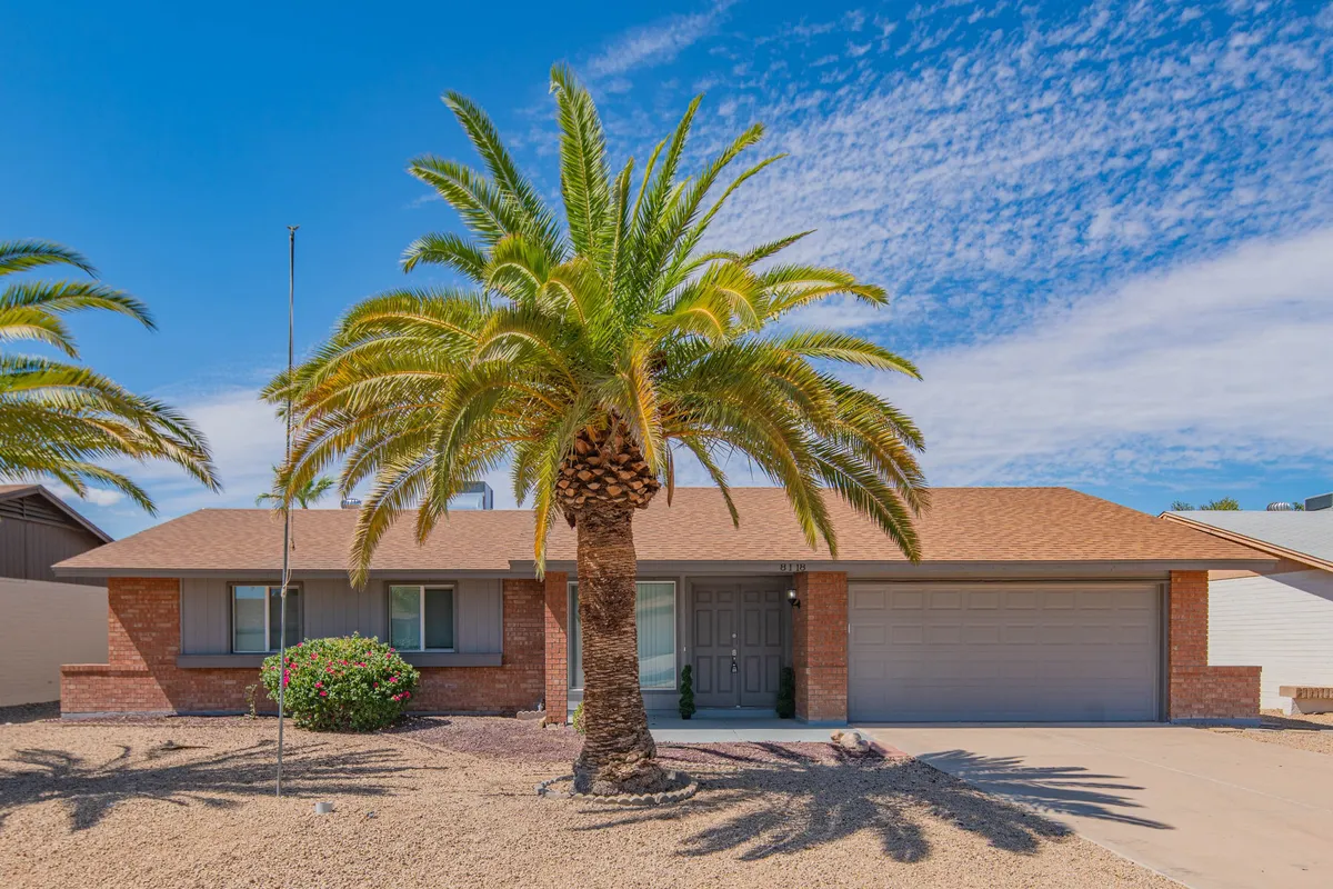 A welcoming exterior shot of the home featuring palm trees, a front door, and a garage door. The setting is bright and cheerful, with plenty of open yard space suggesting opportunities for family gatherings or outdoor barbecues.