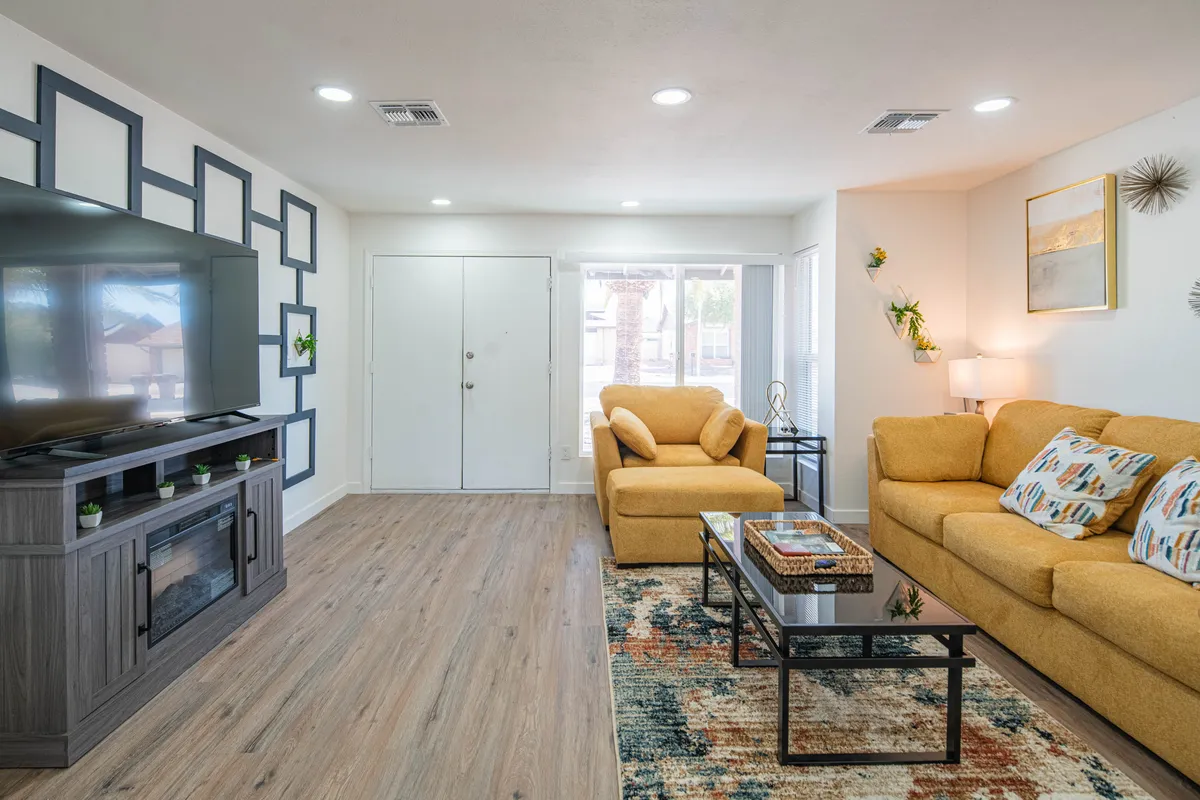 A cozy family room with a large television, comfortable seating, a decorative wall, and a central coffee table. The layout is inviting for group activities, from movie nights to relaxed conversations. The space feels both open and intimate, ideal for various family activities.
